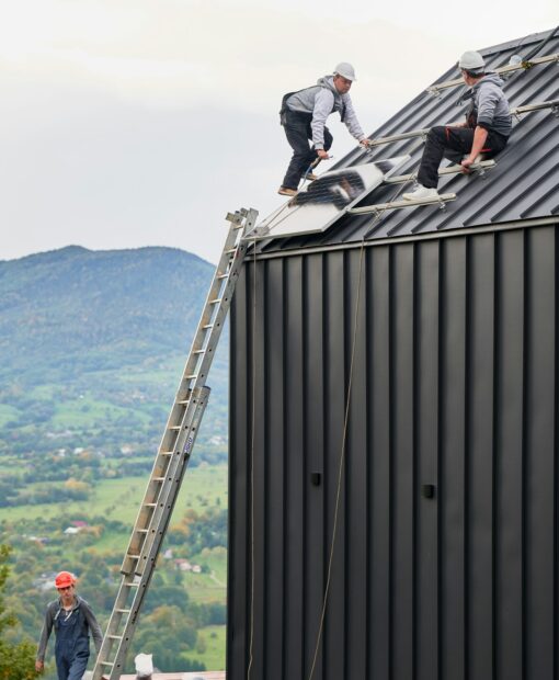 Men workers installing solar panels on roof of house.